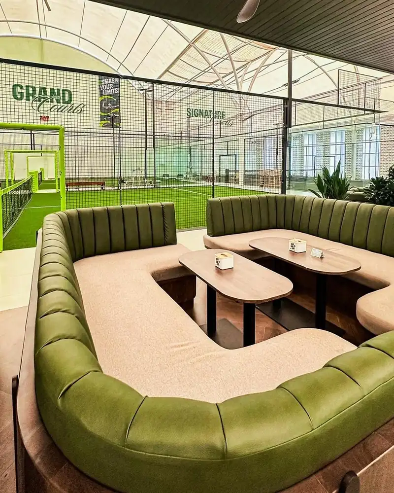 Green velvet lounge beside the Grand Courts at MMT Padel Puri