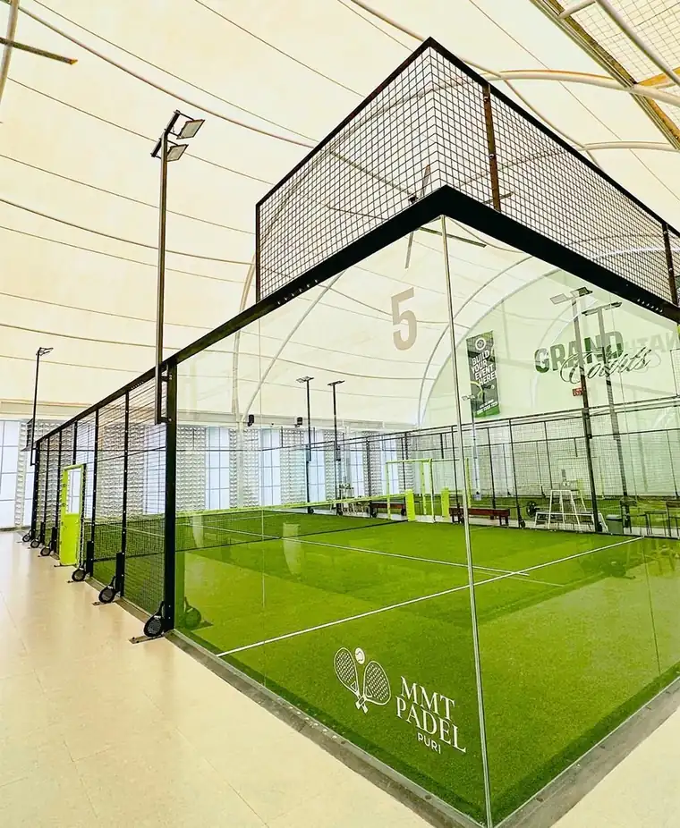 A Grand Court with the MMT Padel Puri crest on the glass and bright green turf